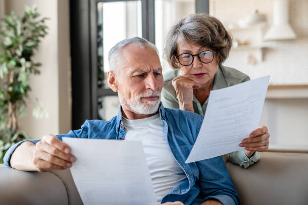 Senior old elderly spouses grandparents reading documents, Do You Need a Lawyer to Make a Living Trust? having issue problem debt with money loss, doing paperwork together at home. Mortgage, loan and commerce procedures